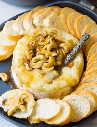 Dying over this Baked Brie with Cashews and Bourbon Brown Sugar Glaze Recipe on ASpicyPerspective.com. #holidays #christmas