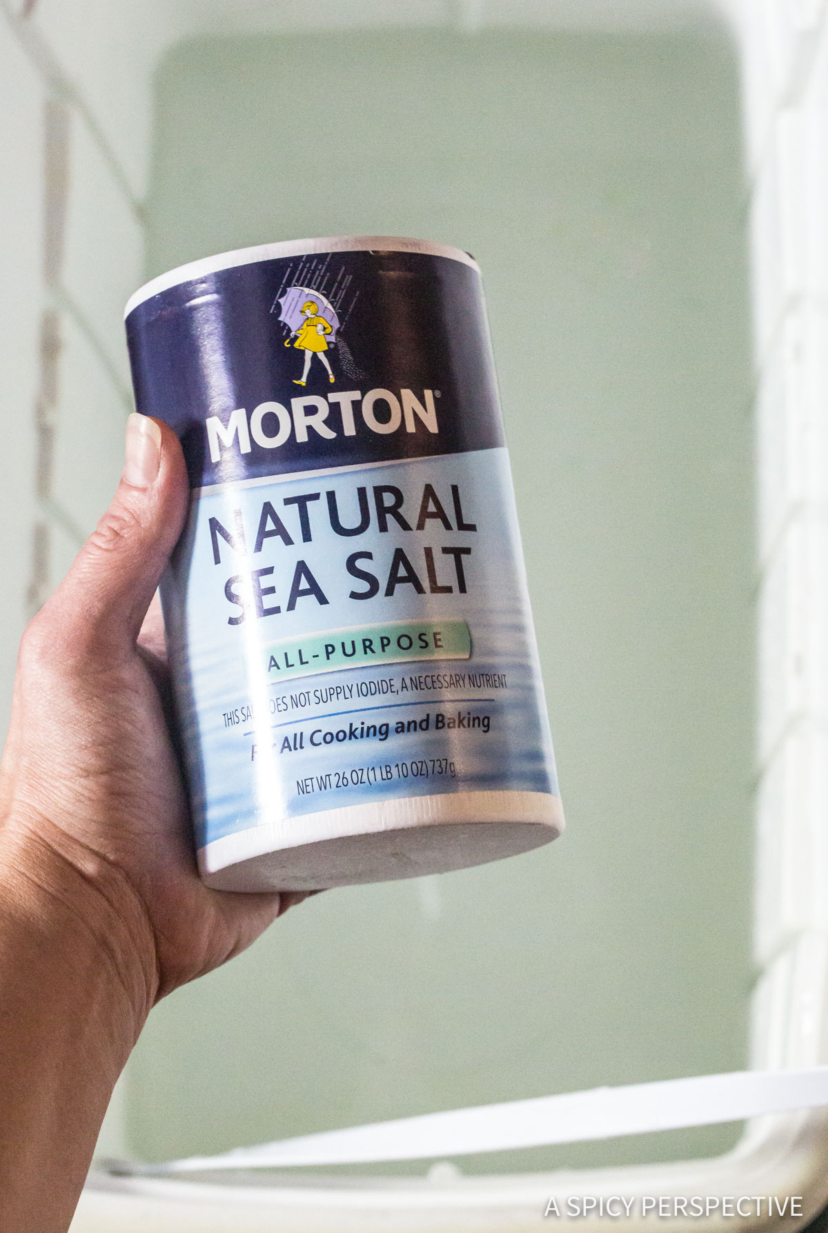 Hand holding a container of natural sea salt for Turkey Brine Recipe.