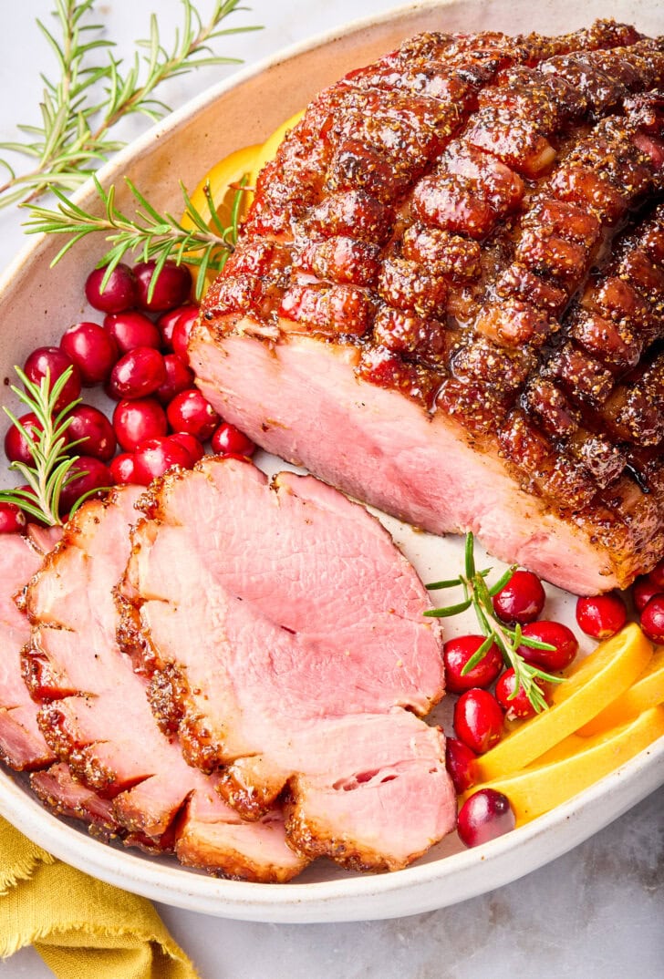Baked ham on a platter with some pieces sliced off.