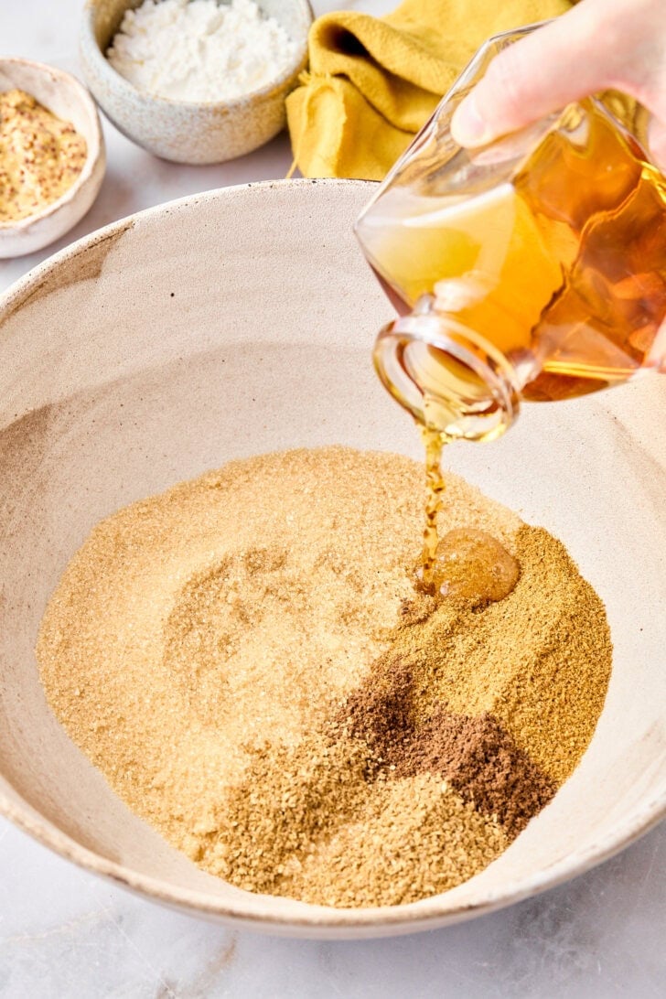 Pouring brandy into a bowl of spices for the brown sugar glaze.