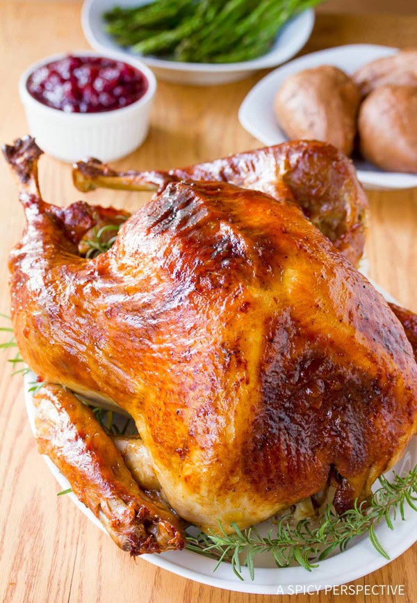 Roast turkey on a serving platter lined with fresh herbs. 

