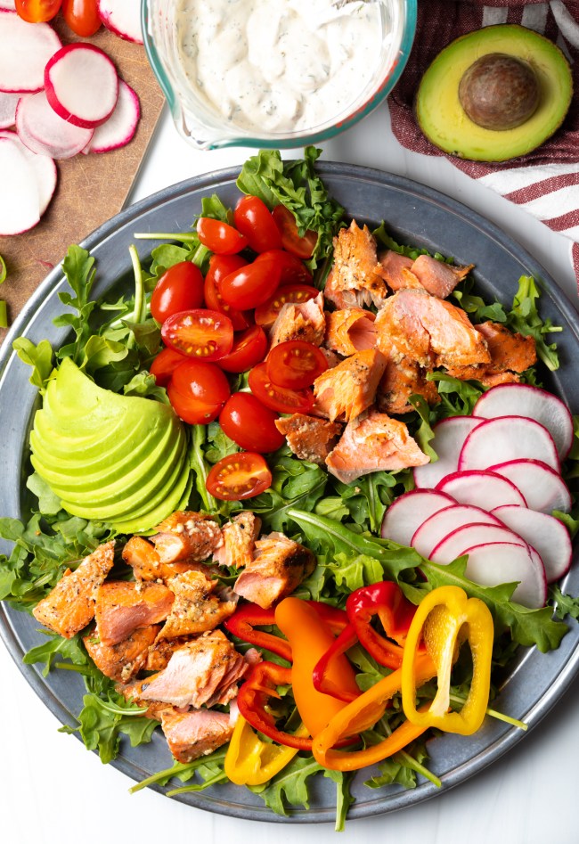 Top down view salad with salmon, veggies, and avocado slices.
