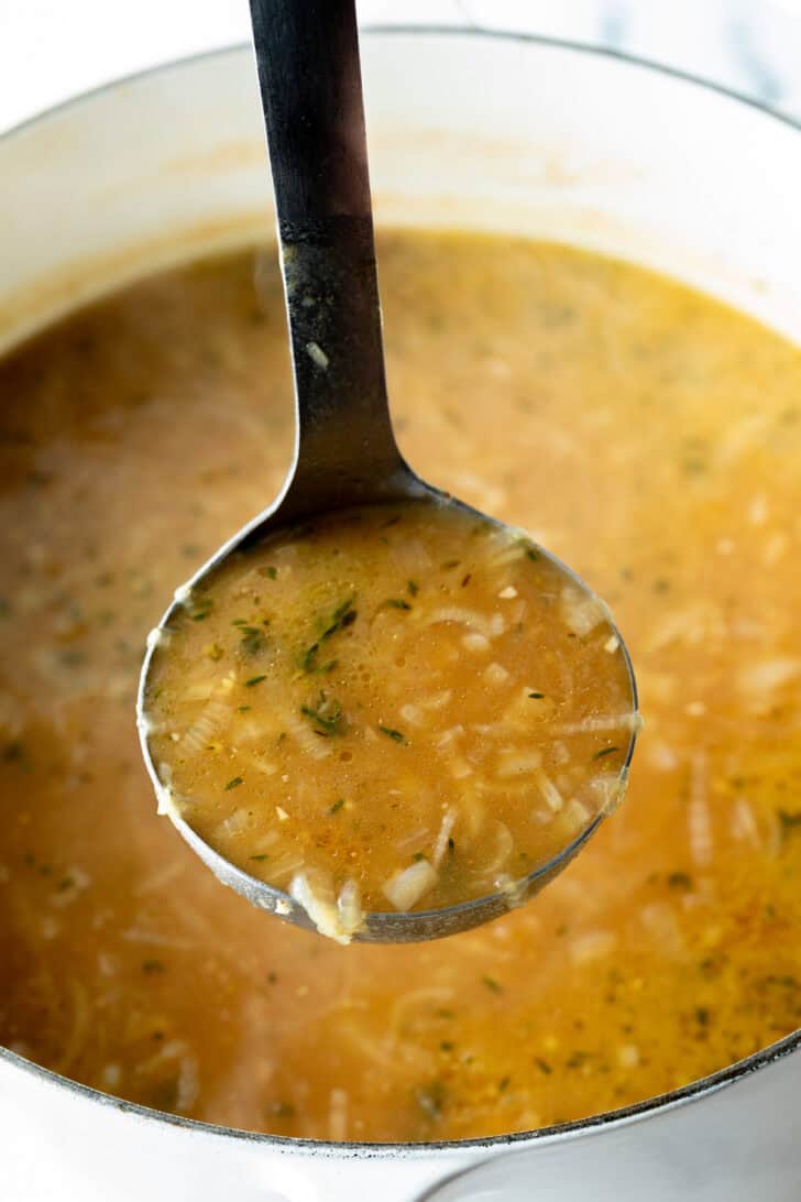 Metal ladle showing onion soup to camera.