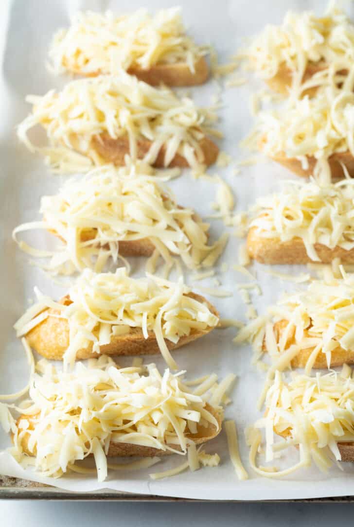 8 slices of baguette topped with shredded cheese.