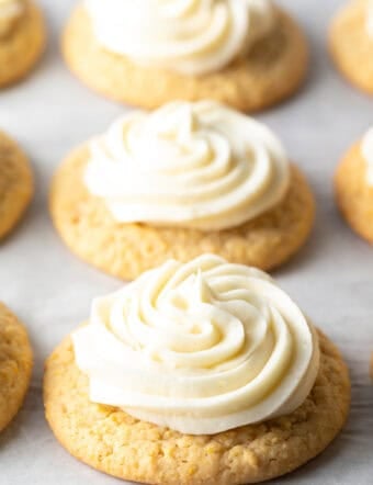 Several honey butter cornbread cookies on a white background, each topped with piped frosting.