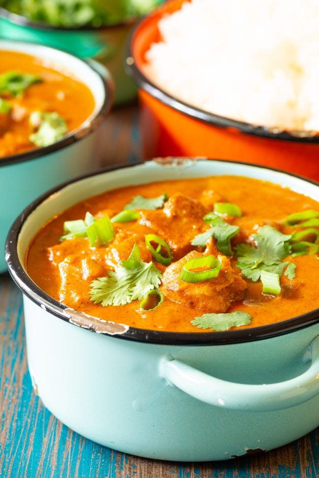 chicken curry in a bowl with fresh herbs on top. 