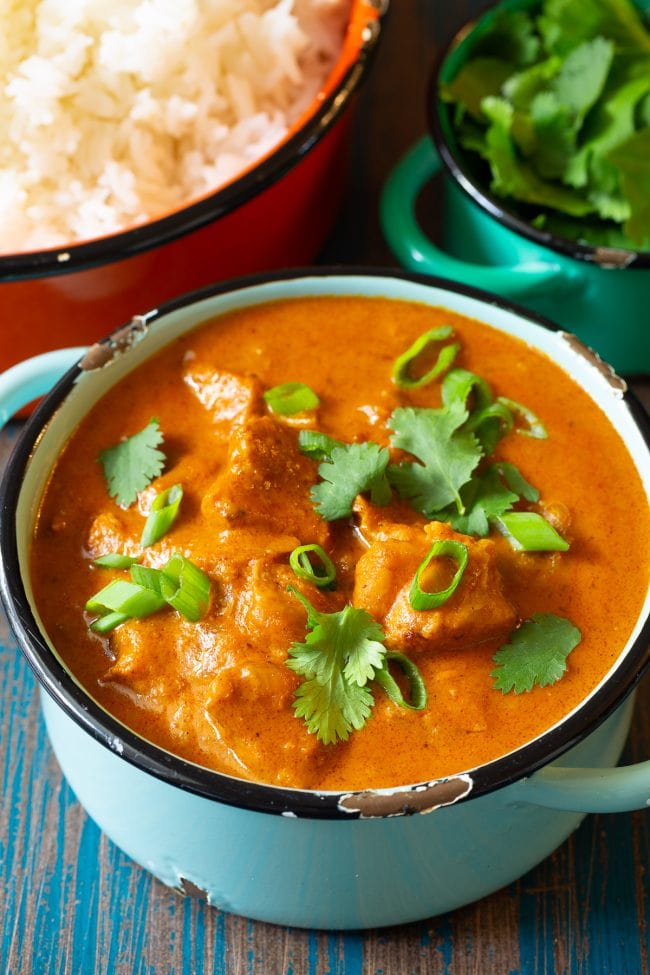 Instant Pot Butter Chicken Curry in a pot with fresh cilantro and green onion on the top.