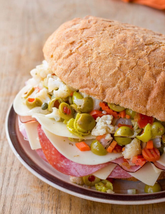Muffuletta #ASpicyPerspective #NewOrleans #Sandwich #Muffuletta #MuffulettaSandwich #MuffulettaRecipe #OliveSalad New Orleans Muffaletta Sandwich served on a plate.