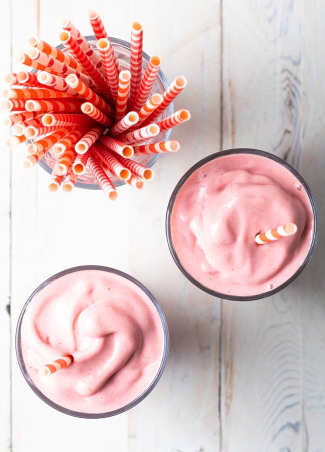 Overhead shot of two glasses with smoothie in them with straws in the too. 